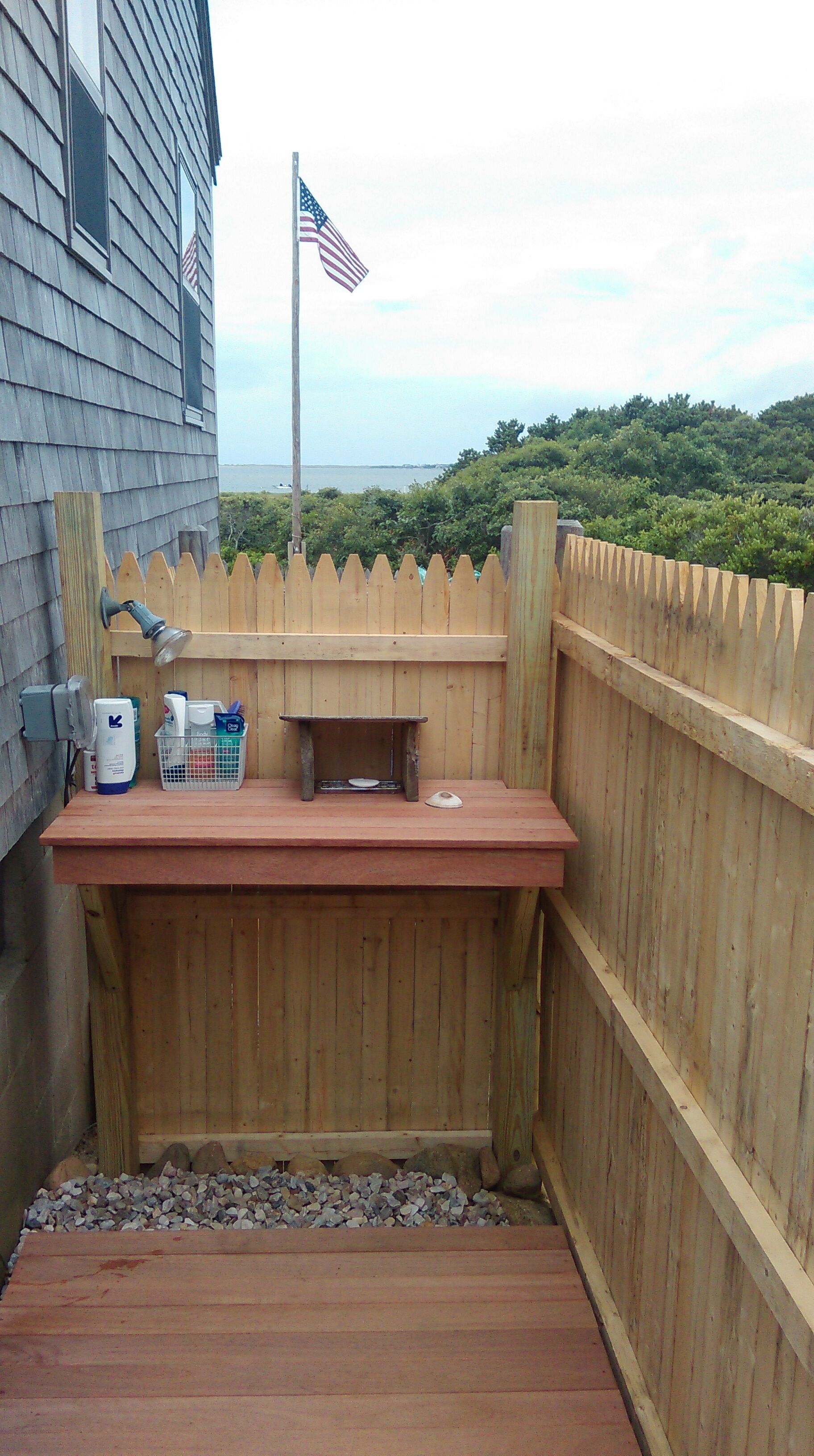Une terrasse en bois avec une table, un drapeau et une vue sur l’océan.