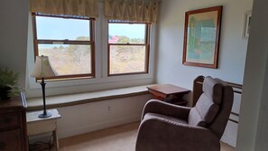 Ein Zimmer mit Fensterbank, einer Lampe, einem Sessel und einer gerahmten Karte an der Wand.