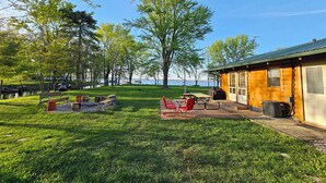 Een houten hut met terras, barbecue en uitzicht op een meer.