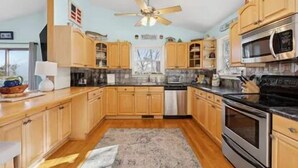 Una cocina con armarios de madera, un horno de acero inoxidable y un ventilador de techo.