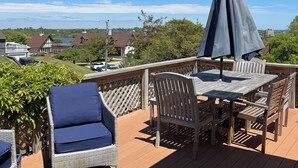 Una terraza de madera con muebles de exterior, incluyendo una mesa y sillas, y una sombrilla.