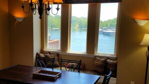 Un comedor con vista a un lago, una lámpara de candelabro y una mesa con bandeja.