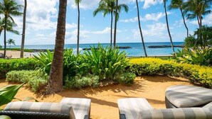 Una zona relax in spiaggia con lettini, palme e vista sull'oceano.
