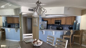 A kitchen with wooden cabinets, a microwave, and a sink. There is a dining table with chairs and a decorative bowl. - Upgraded and Renovated! Beach Chairs Included! Book Spring Break - Great Rates! (Panama City Beach)