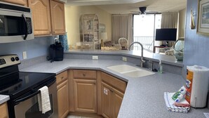 A modern kitchen with granite countertops, wooden cabinets, a microwave, stove, and a sink. - Upgraded and Renovated! Beach Chairs Included! Book Spring Break - Great Rates! (Panama City Beach)