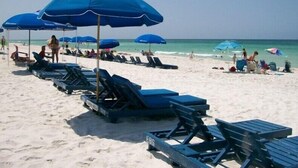A beach with rows of sun loungers and umbrellas, some occupied by people. - Upgraded and Renovated! Beach Chairs Included! Book Spring Break - Great Rates! (Panama City Beach)