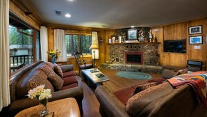 A cozy living room with a stone fireplace, comfortable seating, and a television. - Buss Stop (Wawona)