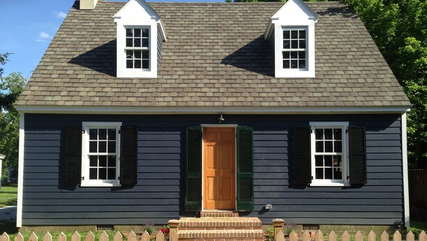 A two-story house with a brick roof, a front door, and a picket fence. - Carpenter St. Cottage In the Heart of St Michaels Village - Large Screened Porch (Saint Michaels)
