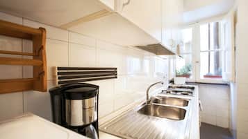 A modern kitchen with white cabinets, stainless steel appliances, and a window providing natural light.