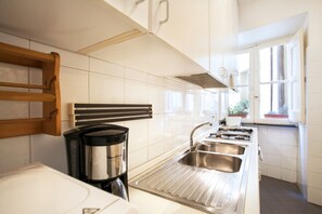 A modern kitchen with white cabinets, stainless steel appliances, and a window providing natural light. - Amazing apartment with 2 bedrooms with ensuite bathrooms - WIFI/Elevator (Roma)