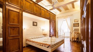 Una camera da letto con un letto a struttura in legno, una testiera bianca e un pavimento in legno con motivo a spina di pesce.