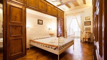A bedroom with a wooden bed frame, a white headboard, and a herringbone-patterned wooden floor.