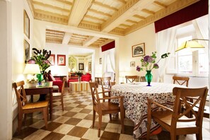A dining area with a checkered floor, wooden chairs, a round table with a floral tablecloth, and a chandelier. - Amazing apartment with 2 bedrooms with ensuite bathrooms - WIFI/Elevator (Roma)