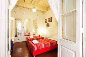 A bedroom with two beds, a mirror, and a hanging light fixture.
