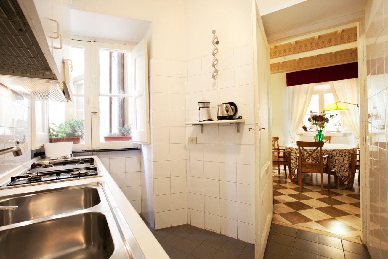 Una cocina con estufa, lavamanos y comedor con mesa y sillas.
