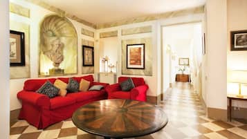 A spacious living area with a checkered floor, red sofas, and a central round table.