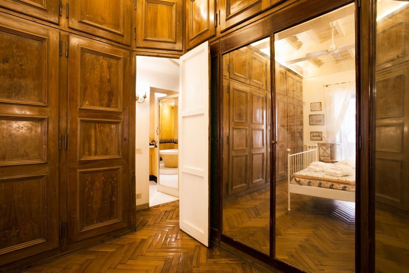 A room with wooden paneling, a bed with a patterned bedspread, and a white radiator.