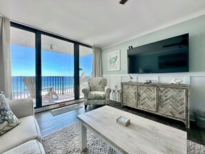 Relax in this stylish living room with a sofa, coffee table, and flat-screen TV, plus a balcony with ocean views.