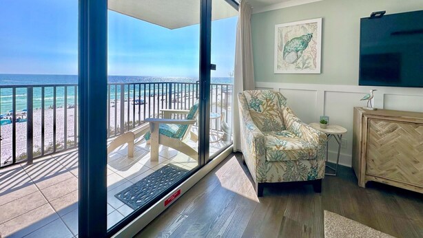 Una habitación con vista a la playa, una silla, una mesita y un armario.