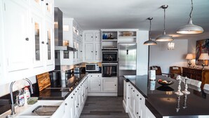 A modern kitchen with white cabinetry, stainless steel appliances, and a black countertop.