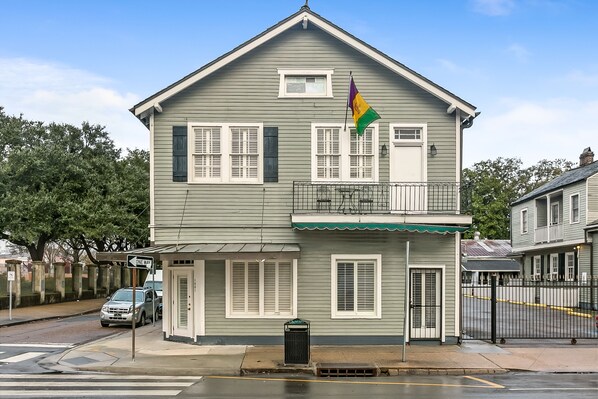 A two-story building with a balcony, a flag, and a street view. - Prime Location, 3 Blocks to Bourbon St. A great space for groups to enjoy NOLA. (New Orleans)