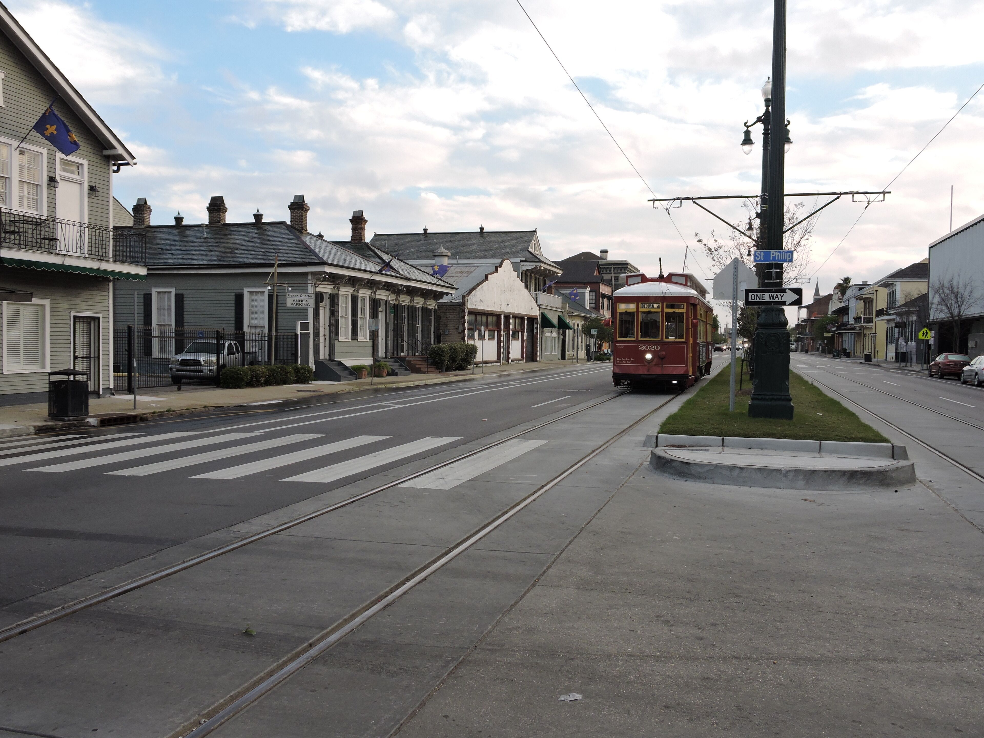 A street with a tram, buildings, and a pedestrian crossing.