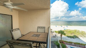 Un balcone con tavolo e sedie, un ventilatore a soffitto e vista sulla spiaggia.