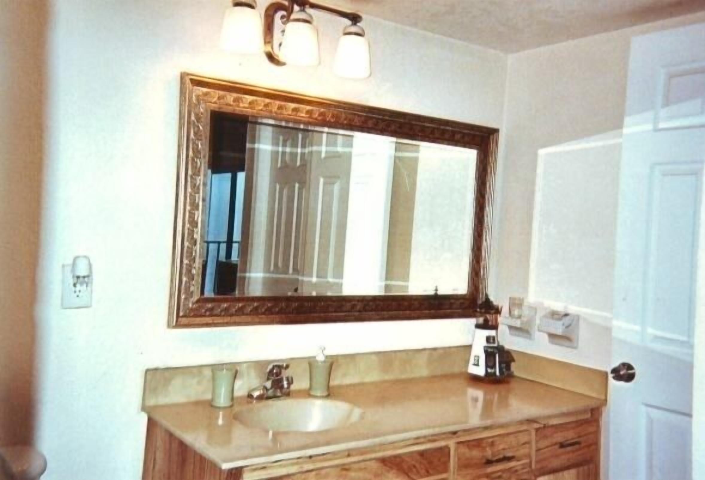 Une salle de bain avec un grand miroir, un lavabo et un meuble-lavabo doté de tiroirs.