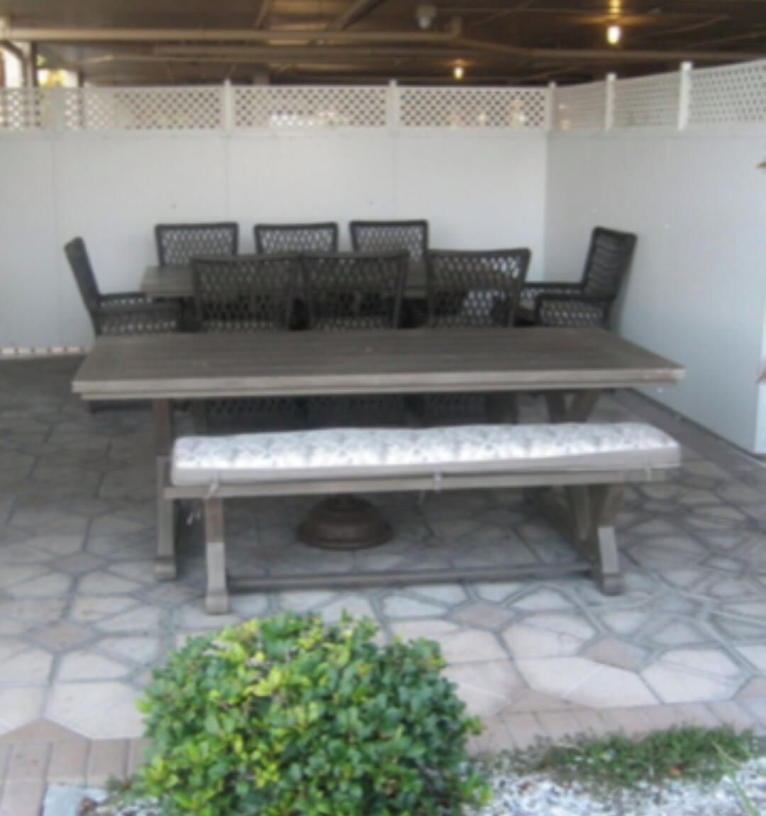 Une terrasse extérieure avec une table et des chaises, un banc et une petite plante verte.