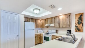 Una cucina moderna con mobili in legno, un frigorifero bianco, un forno a microonde, un fornello e un lavello.