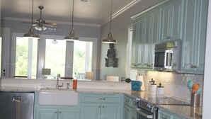 Una cocina con gabinetes color turquesa, un refrigerador de acero inoxidable, un microondas y un ventilador de techo.