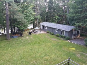 A house with a fenced backyard, a patio with outdoor furniture, and a dock by a body of water.