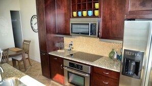 A kitchen with wooden cabinets, a microwave, an oven, a sink, and a water dispenser. - GREAT GALVESTON GETAWAY! STRESS-FREE BEACH VACATION! (Galveston)