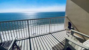 Een balkon met uitzicht op de oceaan, een tafeltje met een beeldje en een stoel.