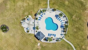 An aerial view of a resort with a central swimming pool surrounded by lounge chairs and palm trees. - 5 minutes to the beach! Cozy 2 King BR 2BA Condo at Myrtlewood Golf Club (Myrtle Beach)