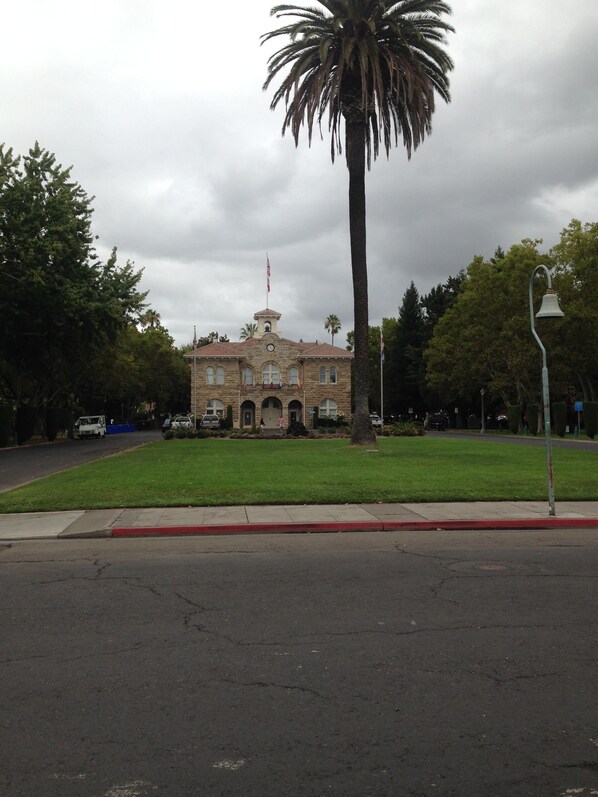A historic building with a clock tower, surrounded by a well-maintained lawn and palm trees.