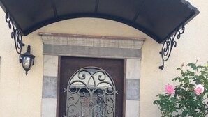 Una puerta marrón con un panel de vidrio decorativo y un toldo negro encima.