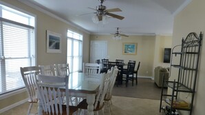 A dining area with a glass-top table surrounded by white chairs, a ceiling fan, and a wine rack against the wall. - 2 min walk to Jenkinson's Beach/Boardwalk. Beautiful, large house for big family (Point Pleasant Beach)