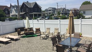 An outdoor patio area with a table and chairs, a covered seating area, and a white fence. - 2 min walk to Jenkinson's Beach/Boardwalk. Beautiful, large house for big family (Point Pleasant Beach)