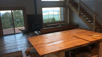 Une pièce spacieuse avec une grande table en bois, un chien et une vue sur l’extérieur grâce à une grande fenêtre.