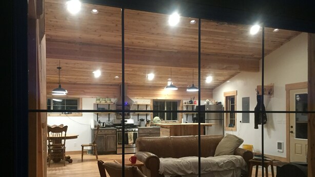 Een gezellige woonkamer met een houten plafond, een bank en een eettafel.