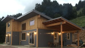 Een huis met twee verdiepingen, een overdekte veranda en een groot raam.