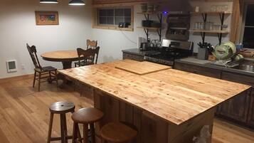 Une cuisine dotée d’un îlot central, de chaises en bois, d’une table à manger et d’un luminaire suspendu.