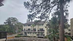 A multi-story building with balconies, a pond with a fountain, and surrounding greenery. - Updated 2 BR/ 2.5 Bath Close to everything you need. (Hilton Head Island)