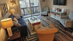 A living room with a sofa, armchairs, a coffee table, a TV, and a bookshelf. - Updated 2 BR/ 2.5 Bath Close to everything you need. (Hilton Head Island)