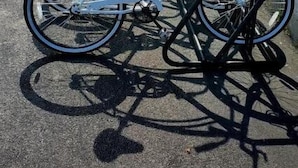 Une rangée de vélos est garée contre un bâtiment dont le mur est en briques et qui possède un balcon.