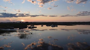 Un plan d’eau paisible, avec des bateaux et un coucher de soleil en arrière-plan.