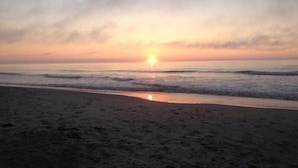 Une plage avec un coucher de soleil sur l’océan.