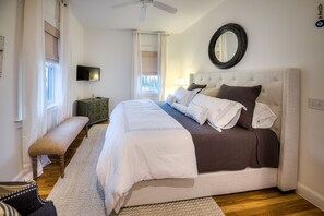 Un dormitorio con una cama grande, un banco, un televisor y un espejo en la pared.
