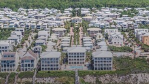 A coastal residential area with multiple beachfront properties, including houses and a large building with a swimming pool.